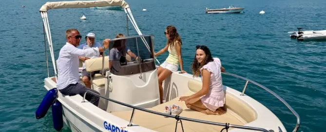 Ein Motorboot mit mehreren Passagieren fährt auf ruhigem Wasser in einer Berglandschaft.