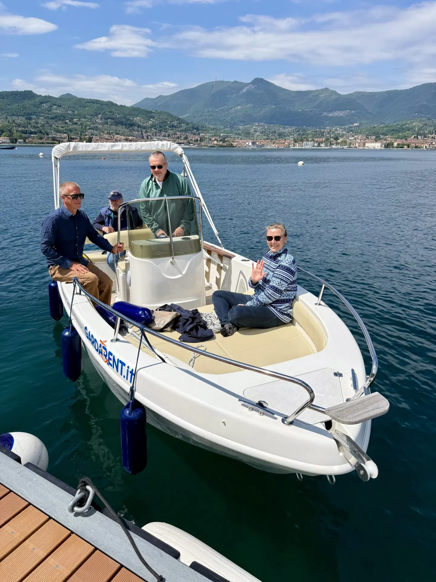 ab-sportbootschule_pruefung_30-04-2026_06 Four people relax on a motorboat at Lake Garda near Malcesine after a SBF See und Binnen exam, with mountains and clear water behind them.