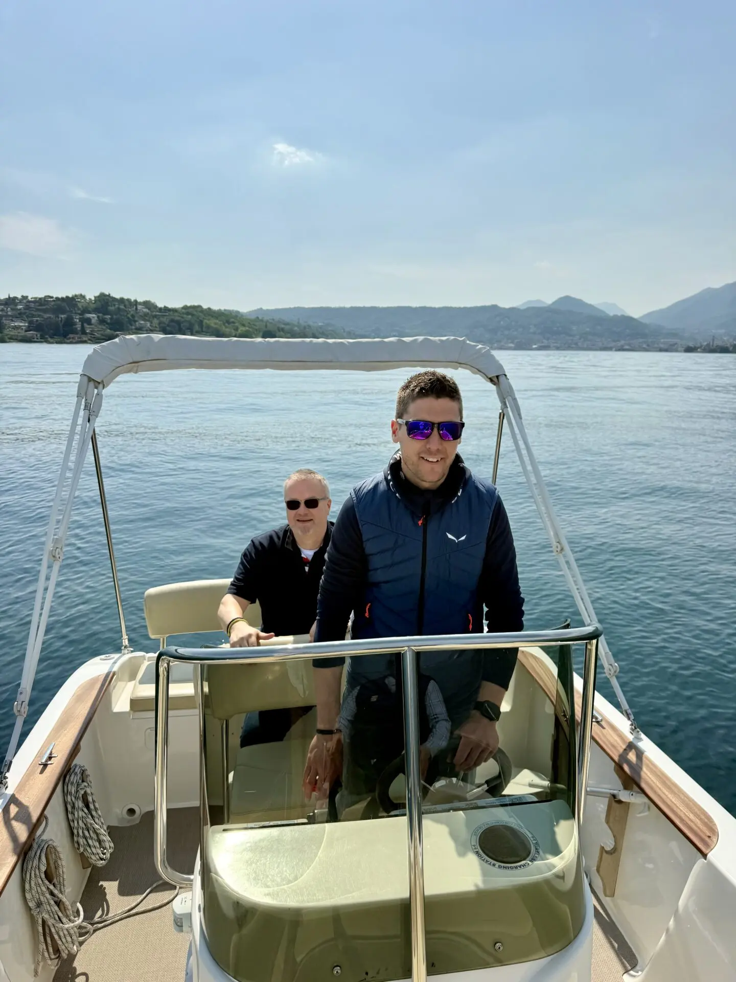 ab-sportbootschule_pruefung_30-04-2026_09 Bei der SBF See und Binnen Prüfung am Gardasee steuern zwei Männer ein Motorboot, während im Hintergrund die Uferlandschaft von Zorzi sichtbar ist.