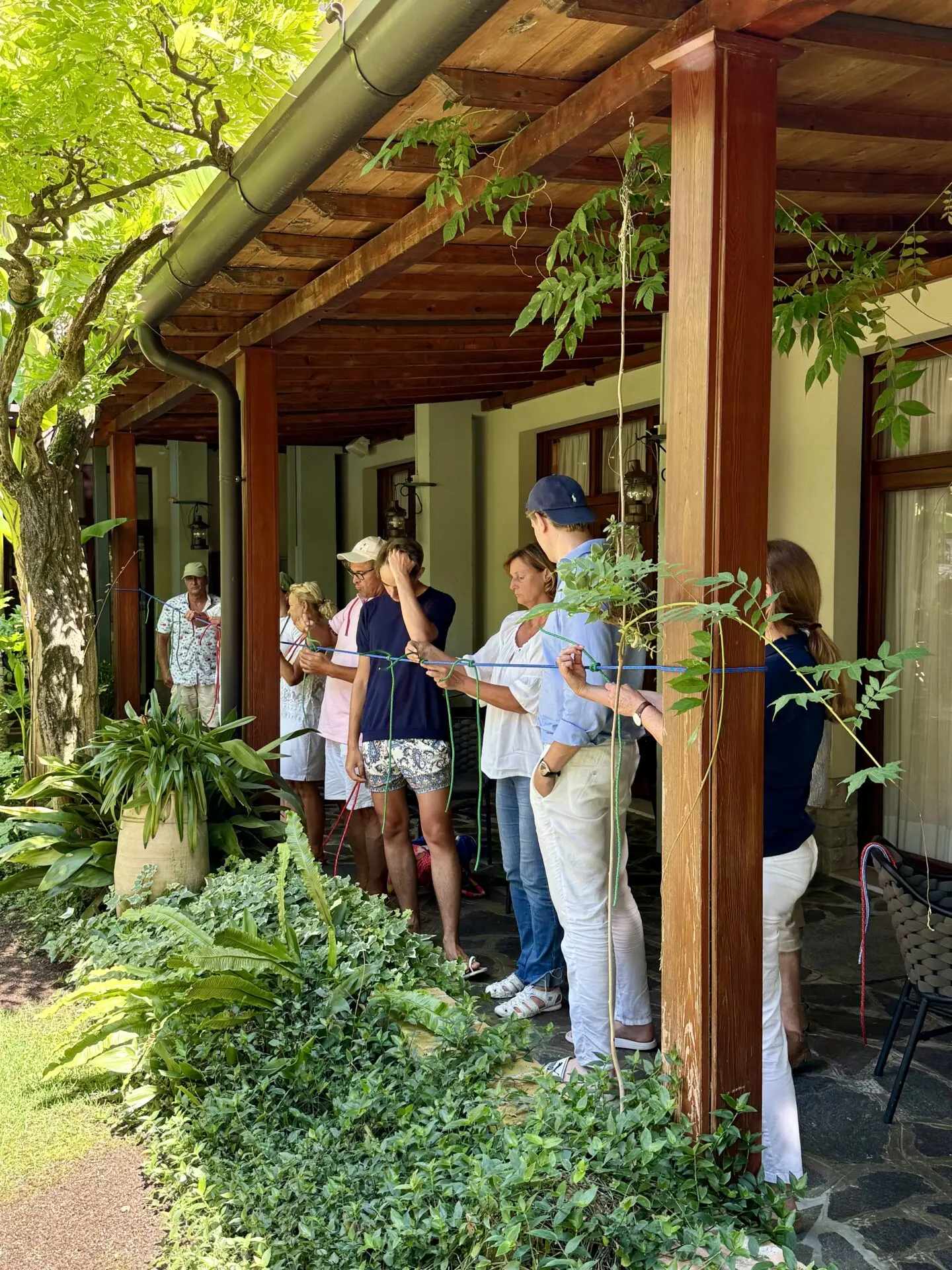 ab-sportbootschule_pruefung_09-07-2026_05 Mehrere Teilnehmer stehen unter der Holzveranda des Hotel Garden Zorzi und halten farbige Leinen bei der Bootsprüfung.