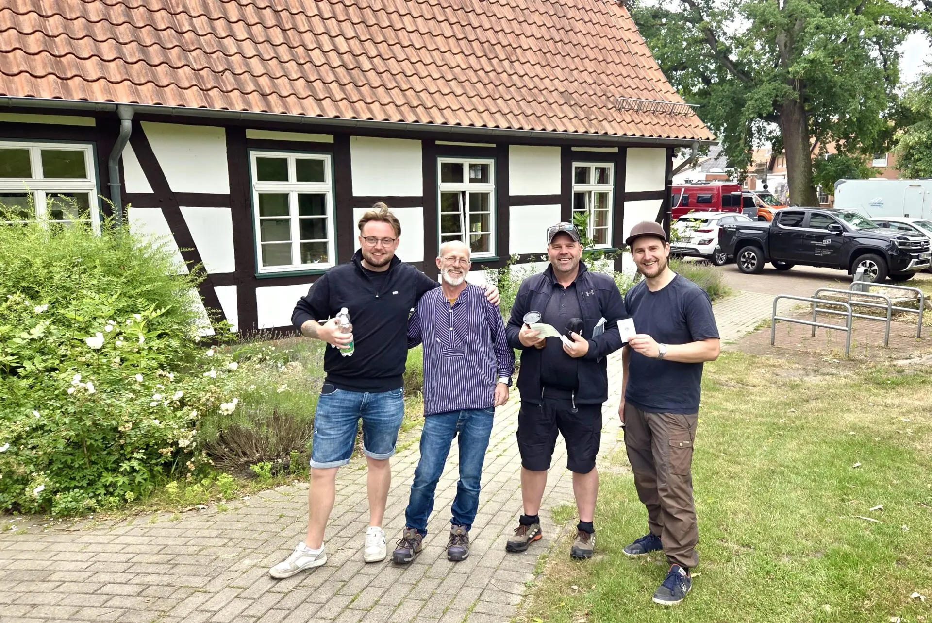 Vier Männer stehen vor einem Fachwerkhaus und halten nach einer bestandenen SBF-See-und-Binnen-Prüfung Zertifikate.