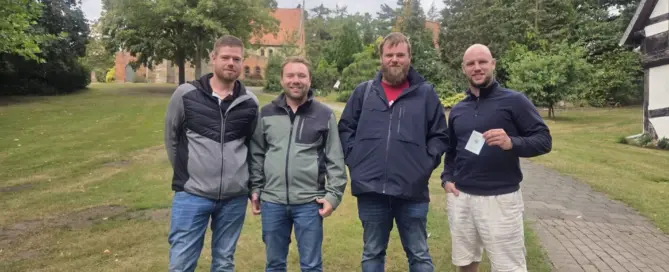 Vier Männer stehen nach bestandener Sportbootführerschein-Prüfung auf einer begrünten Anlage an der Weser zusammen.